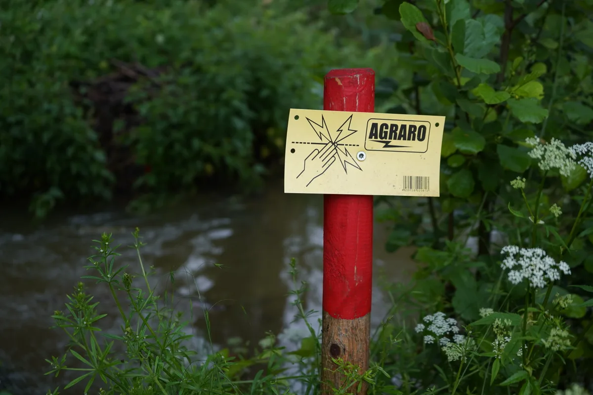 Ein Schild hängt an einem Holzpfahl.